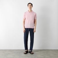 Thumbnail of Man wearing a pink polo shirt and navy pants standing against a plain background